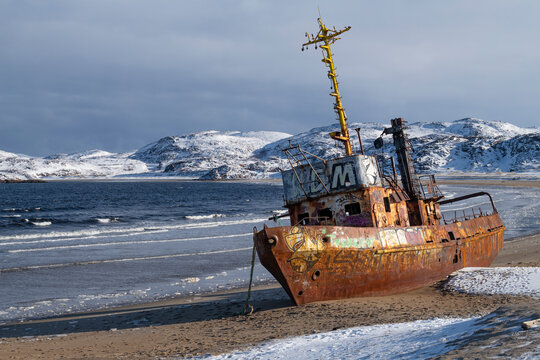 The old fishing trawler on the shore of Teriberka Bay on a March day. Murmansk Region
