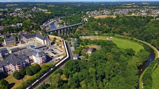 Drone panorama of the Rance River environment with the roman Viaduc de Dinan and Port de Dinan in the background on green valley near residential district and surrounding forest, Cotes-d'Armor, France