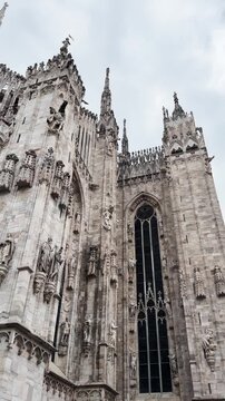 Upward view of Milan Cathedral facade with ornate Gothic details and statues