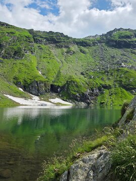 Emerald waters of Balea glacial lake with mountain reflection, Romania