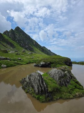 Rocky islet in a muddy glacial lake in Fagaras mountains, Romania