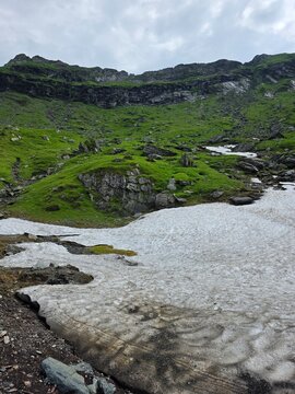 Melting snow patch on green mountain slope in Fagaras mountains, Romania