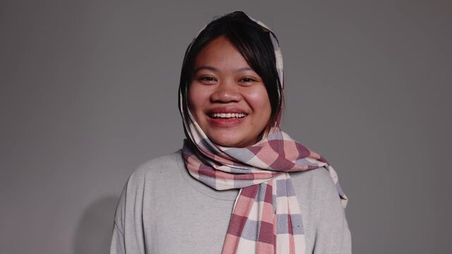 Happy portrait of a serious young Asian woman wearing a traditional checkered scarf wrapped around her head.