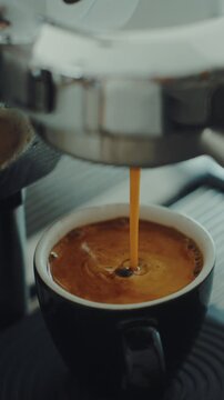 4K Pouring coffee stream from professional machine in cup. Barista man making double espresso, using filter holder. Flowing fresh ground coffee. Drinking roasted black coffee in the morning.	
