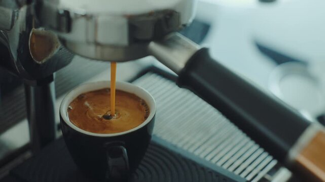 4K Pouring coffee stream from professional machine in cup. Barista man making double espresso, using filter holder. Flowing fresh ground coffee. Drinking roasted black coffee in the morning.	
