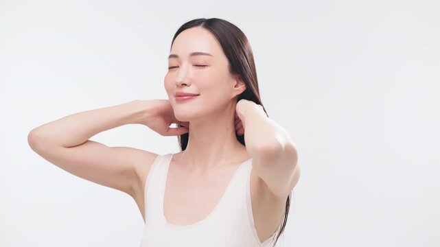 両手で美しい黒髪を後ろにかき上げる日本人女性（ヘアケア・美容・ツヤ・動作）