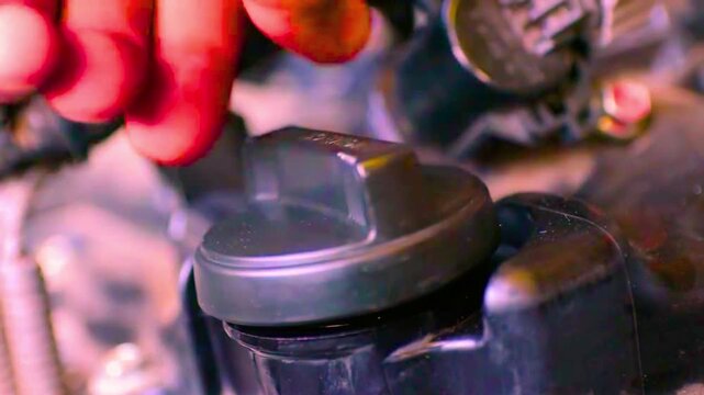 Mechanic hand tightening black oil filler cap on car engine close up