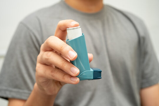 Asthma and chronic obstructive pulmonary disease COPD, Asian young man using metered dose inhaler MDI.