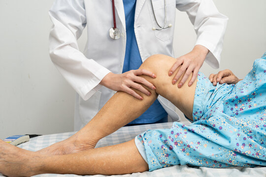 Doctor checking Asian elderly woman patient knee replacement surgery in hospital.