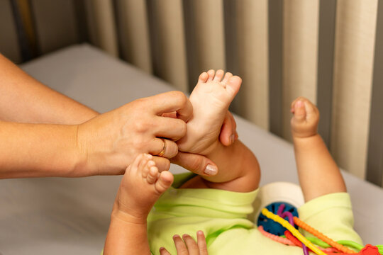 Mother Tickling Baby Son Sole During Play At Home