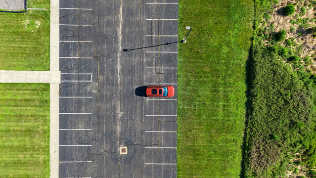 Red car parked alone in empty parking lot