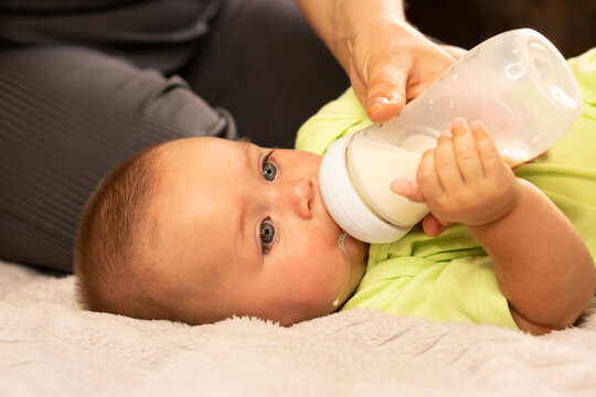 Mother Supports Bottle While Baby Boy Drinks Milk