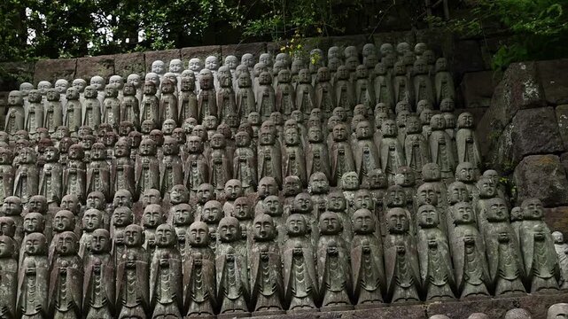 Close-up of many ancient stone Buddhist statues in Japan, arranged in rows with detailed faces and robes. Sacred temple background for religion, travel and heritage themes.