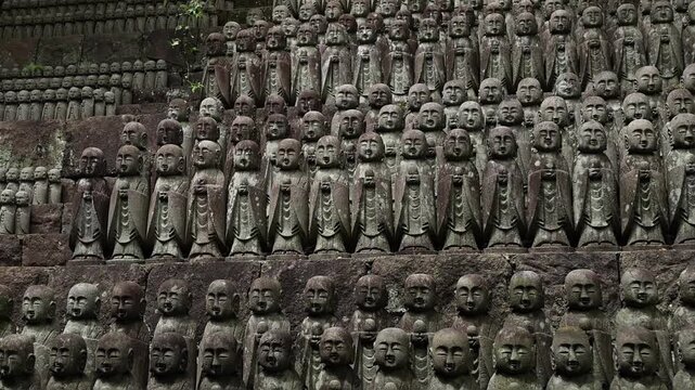 Weathered Jizo statues in a Japanese Buddhist temple, showing rows of small carved figures with calm expressions and traditional spiritual symbolism.