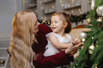 Obraz premium Mother and daughter joyfully celebrating new year by christmas tree for holiday design