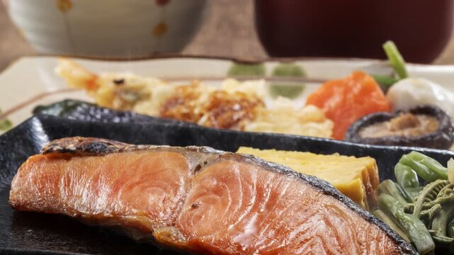 Grilled salmon with Japanese side dishes on elegant dark slate platter