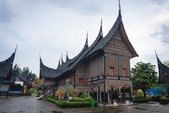 Traditional Minangkabau Rumah Gadang with distinctive curved roofs, wooden architecture, ornate details, and landscaped surroundings.