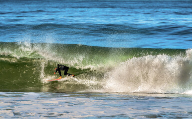 Surfer riding a powerful wave, carving through the water with spray flying © EJ