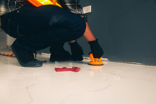 Technician laying tiles using a suction cup machine.