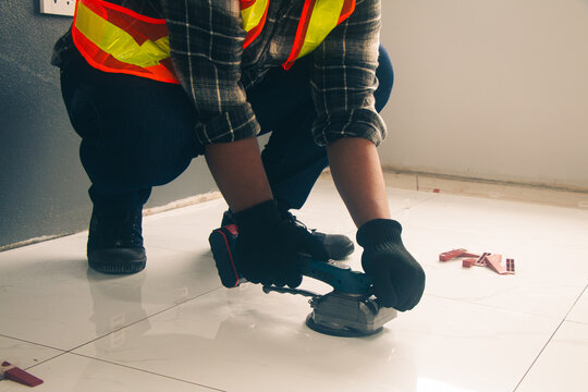 Technician laying tiles using a tile vibrator.