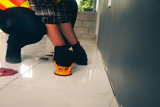 Technician laying tiles using a suction cup machine.