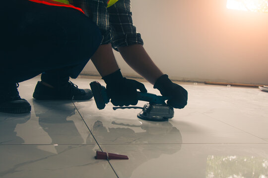 Technician laying tiles using a tile vibrator.