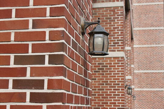 Red brick wall corner with classic wall-mounted lantern at a building entrance