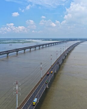 Aerial view of Jamuna Bridge spanning the Jamuna River with vehicles traveling on the road and power lines along the structure in Tangail District, Dhaka Division, Bangladesh.