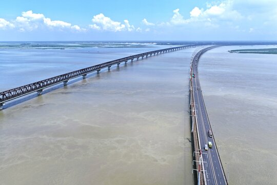 Aerial view of Jamuna Bridge spanning the wide Jamuna River with clear blue sky and calm water in Tangail District, Dhaka Division, Bangladesh.