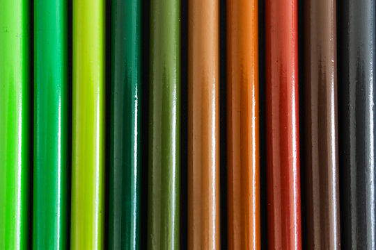 close-up of colored pencil barrels neatly lined up in colour wheel order, concept of creativity and education