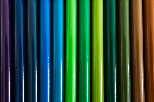 close-up of colored pencil barrels neatly lined up in colour wheel order, concept of creativity and education