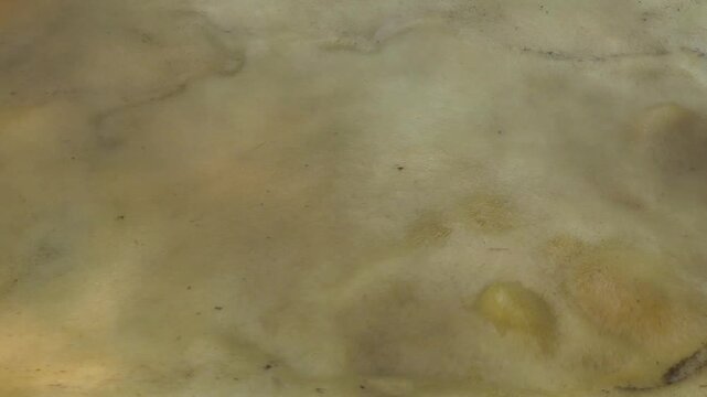 In a large rectangular pot, raw sugarcane juice is heated to a thick, red color to make jaggery.