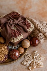 Fototapeta premium Cocoa brown wrapped gift box with a wide ribbon bow and crochet accents on a golden surface for elegant holiday card designs