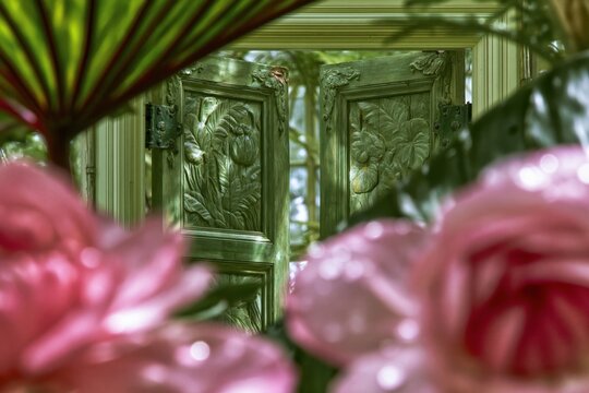Ornate carved wooden double doors in moss green, featuring botanical relief and aged brass hardware for antique architectural and interior decor