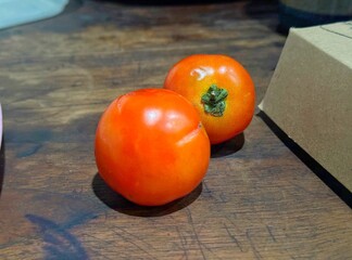Two ripe tomatoes rest on a wooden surface © Ahmad