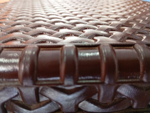 Close up angle view of brown woven plastic stool seat edge with geometric pattern geometric furniture material