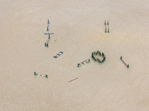 Aerial view of a horse show jumping course with colorful obstacles set on a sandy arena in Anyksciai, Utena County, Lithuania.