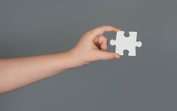 Solving problem starts with single puzzle. Solving concept shows logical creative thinking. Hand gesture suggests solving business challenge. Background space makes solving message.