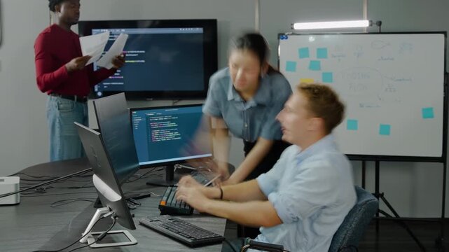 Dynamic timelapse of a diverse IT team in a modern corporate office. A focused male programmer codes at his desk while busy coworkers walk fast, collaborate, and discuss urgent project deadlines.