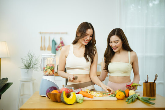 healthy women cooking with kitchen food; women cooking at home. healthy guides buyer choices, women frames the scene, and cooking adds useful meaning. Clear visual context supports stock buyers.