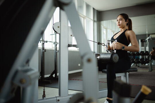 fitness health strength with cable machine; a woman using a. fitness guides buyer choices, health frames the scene, and strength adds useful meaning. Clear visual context supports stock buyers.