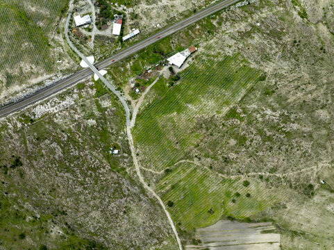 Aerial view of the Santiago Matatlan mezcal factory surrounded by rows of agave plants, a nearby highway, and arid terrain in Santiago Matatlan, Oaxaca, Mexico.