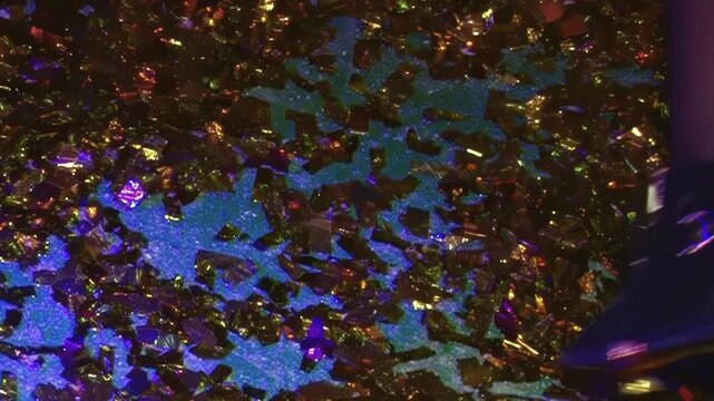 Golden confetti sparkles under neon nightclub lights as people in fishnets dance and celebrate during an energetic late night event filled with rhythmic movement and vibrant club atmosphere