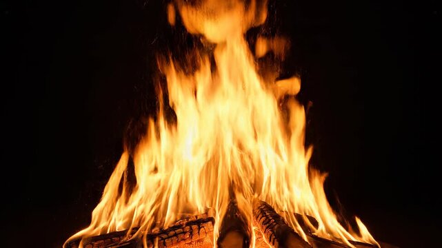 Campfire flames burning with cinematic motion against a dark background during evening