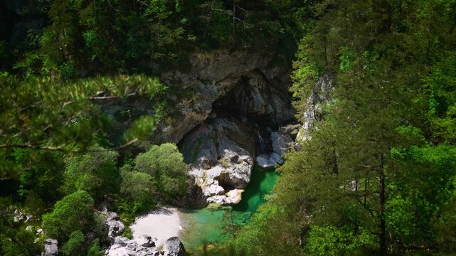 Cascading wild stream forming a beautiful emerald green swimming hole between rocks at Pozze Smeraldine