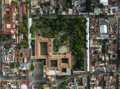 Aerial view of the historic Templo de Santo Domingo de Guzman and its lush botanical garden surrounded by dense colonial rooftops and urban streets in Oaxaca de Juarez, Oaxaca, Mexico.