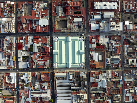 Aerial view of the central market with its distinctive light green roof surrounded by dense urban blocks and red-tiled rooftops in Oaxaca de Juarez, Oaxaca, Mexico.
