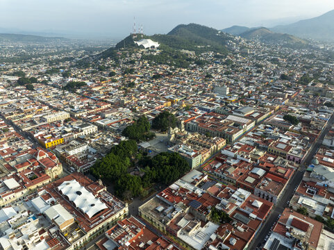 Aerial view of the historic city center of Oaxaca de Juarez featuring the cathedral, colonial architecture, and dense urban rooftops in Oaxaca de Juarez, Oaxaca, Mexico.
