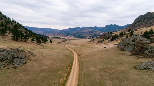 The winding dirt road through a rolling valley landscape under cloudy skies