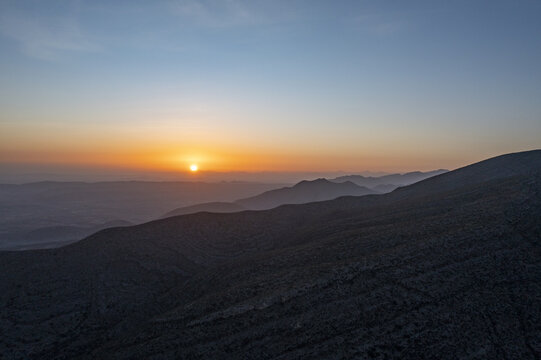Aerial view of the sun setting over the rugged mountain ranges in the desert landscape, Parras de la Fuente, Coahuila de Zaragoza, Mexico.